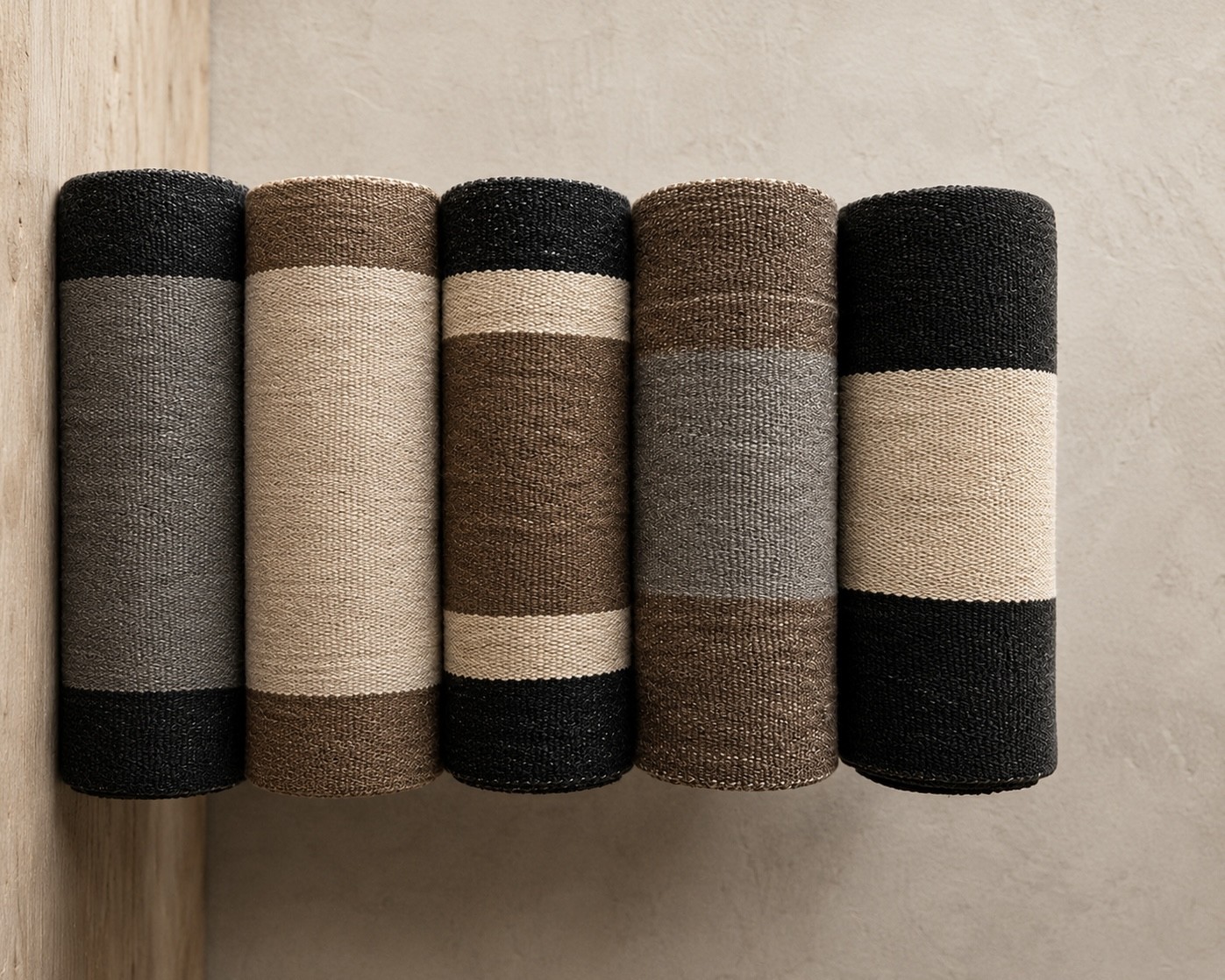 Row of rolled handwoven goat hair rugs and runners in striped colourways